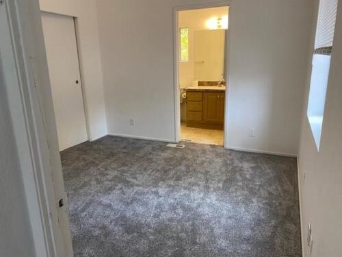 An empty room with gray carpet and a door.