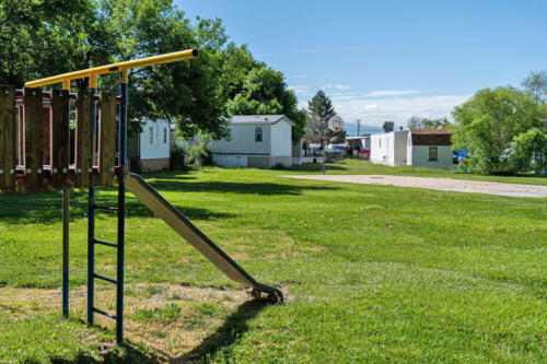 A playground with a slide in a grassy area.